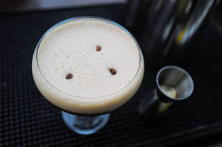 Coffee beans are sprinkled on a glass of espresso martini at a bar in Accra