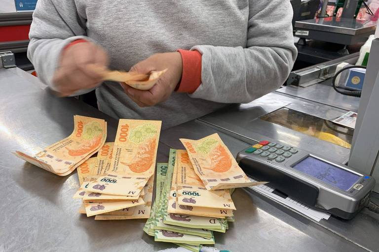 Caixa de supermercado conta notas de pesos ao receber pagamento de cliente na Argentina