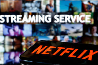 FILE PHOTO: A smartphone with the Netflix logo lies in front of displayed 