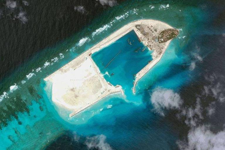 Imagem aérea de recife mostra banco de areia cercado por água, com um grande retângulo de água no meio 