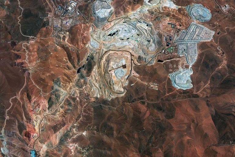 Imagem aérea mostra paisagem marrom montanhosa cortada por manchas brancas das minas de cobre