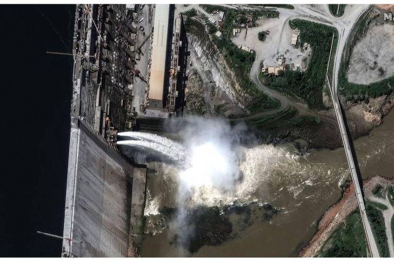 Imagem aérea mostra vertedouro de água de barragem jogando água em rio