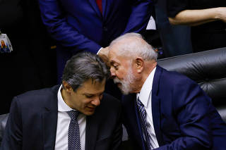 Brazil's President Luiz Inacio Lula da Silva talks with Brazil's Finance Minister Fernando Haddad during a session to promulgate the new tax reform at the National Congress in Brasilia,