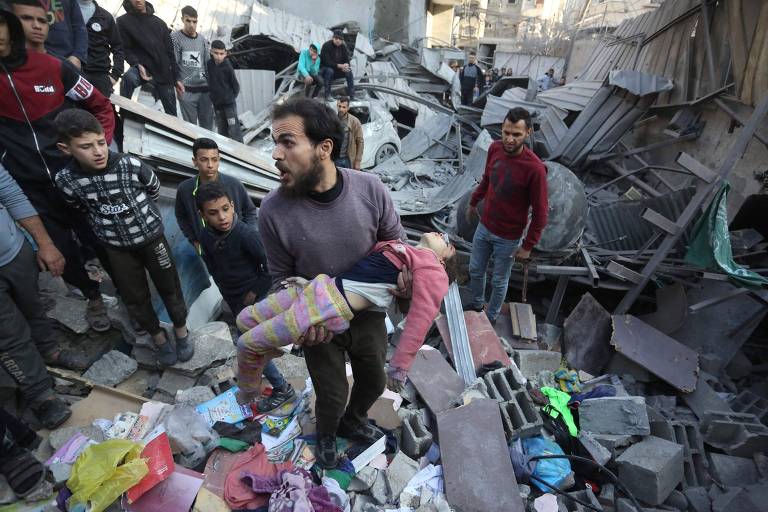 Palestino carrega corpo de criança retirado de destroços em Zawayda, na área central da Faixa de Gaza