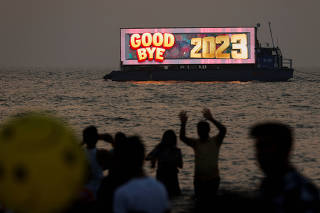 People watch the last sunset of the year from a beach on New Year's eve in Mumbai