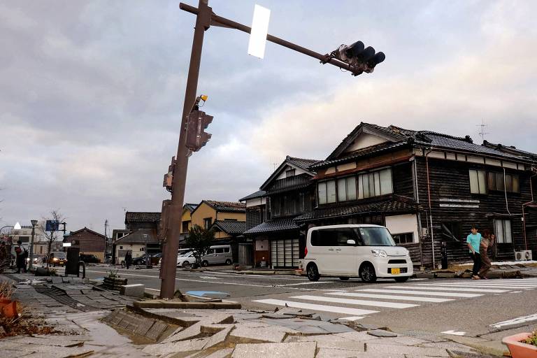 Carro passa em frente à calçada gravemente danificada na cidade de Wajima, na província de Ishikawa, no Japão, após sismo