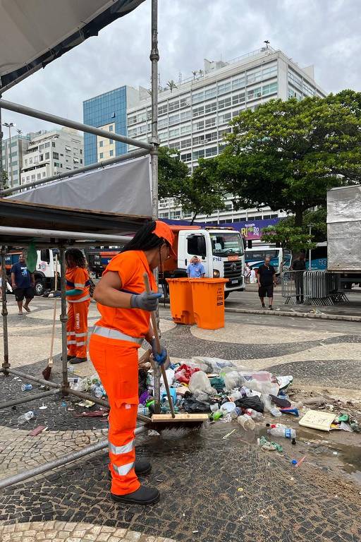 Trabalhadora com uniforme laranja junta lixo com uma vassoura