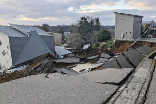A view of a collapsed road and houses because of an earthquake in Wajima