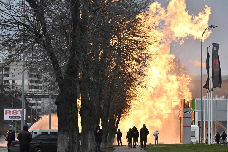 Pessoas observam fogo provocado por ataque de míssil em Kiev