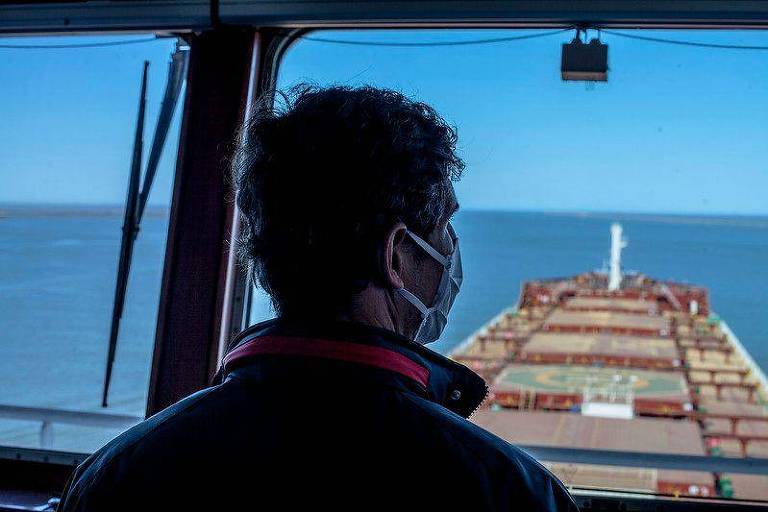 Sombra de homem de costas observando mar da janela de navio
