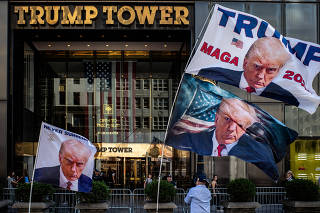 A former U.S. President Donald Trump's supporter places flags depicting him at Trump Tower in New York City