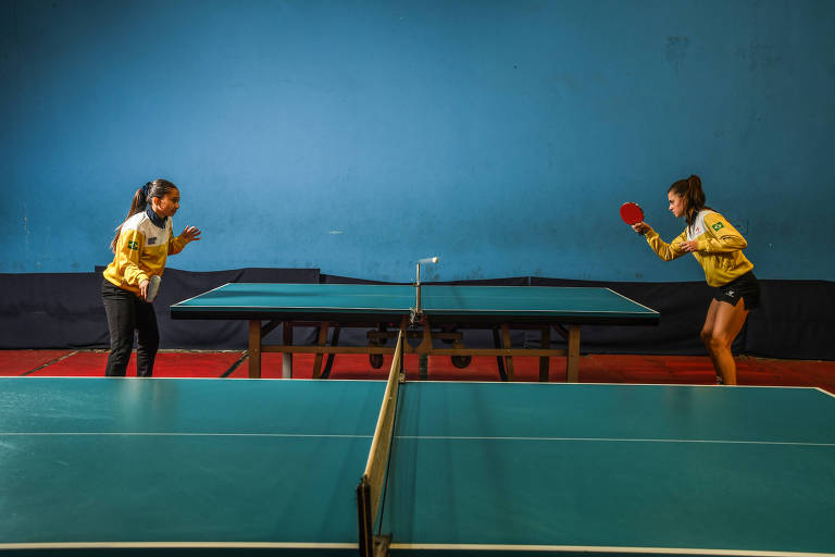 Duas mulheres jogam tênis de mesa