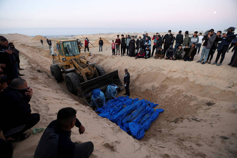 Palestinos mortos em ataques aéreos em Gaza são enterrados em vala comum na cidade de Rafah, no sul do território