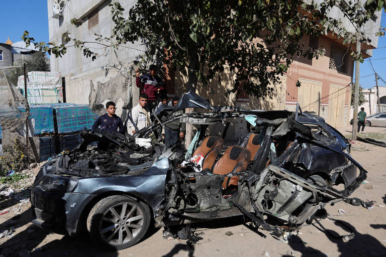 Palestinos observam destroços de carro em que estavam jornalistas atingido por ataque aéreo em Rafah