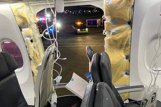 FILE PHOTO: Passenger oxygen masks hang from the roof next to a missing window and a portion of a side wall of an Alaska Airlines Flight 1282, in Portland, Oregon