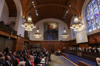 People sit inside the International Court of Justice (ICJ) on the day of the trial to hear a request for emergency measures by South Africa, who asked the court to order Israel to stop its military actions in Gaza, in The Hague