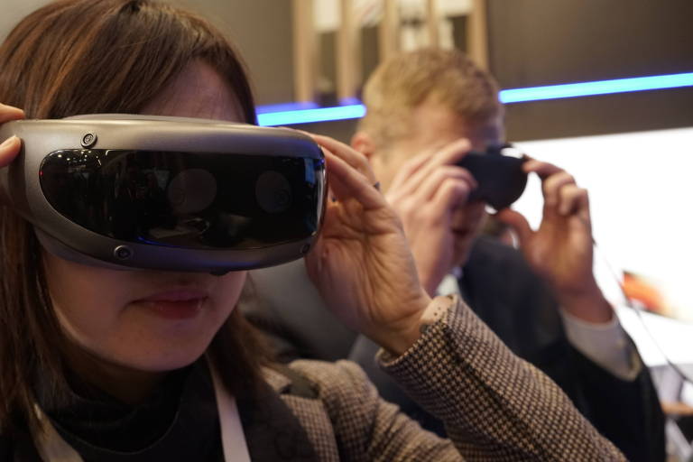 Mulher e homem usam óculos de realidade virtual durante a feira CES