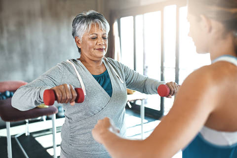 Coaching, halteres e fitness com idosa e personal trainer para apoio, saúde ou fisioterapia. Treinamento, levantamento de peso e treino com cliente sênior e treinadora para exercícios para idosos