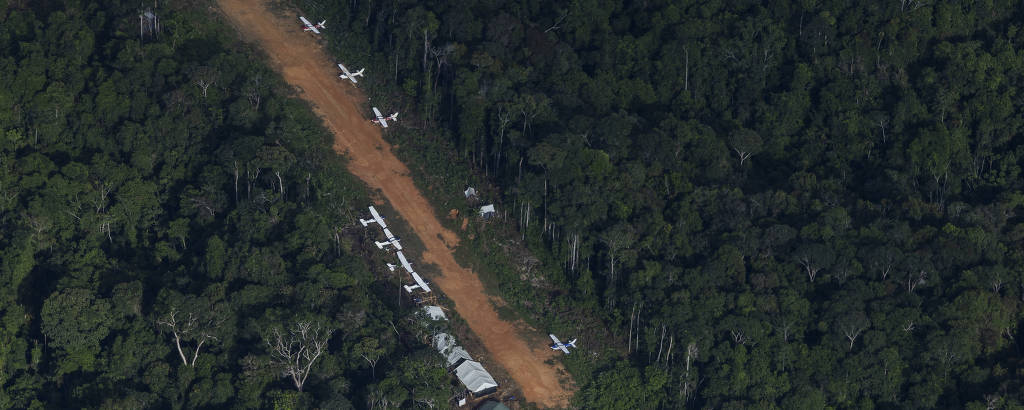 imagem aérea mostra pista de pouso com edificações e vários aviões ao longo do trajeto