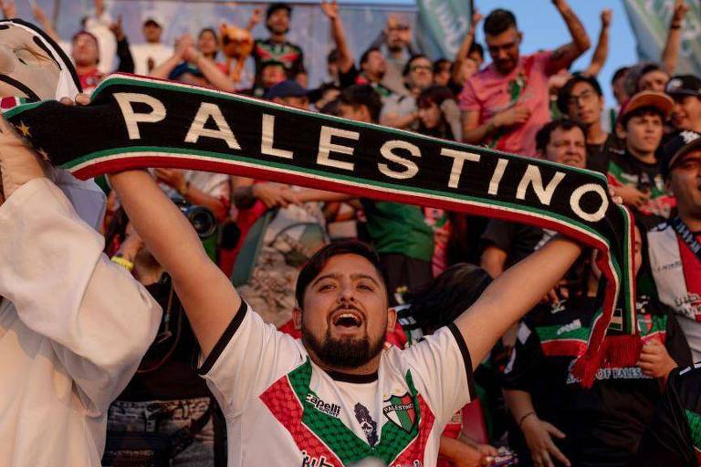 Homem em torcida ergue faixa onde se lê: 'Palestino'