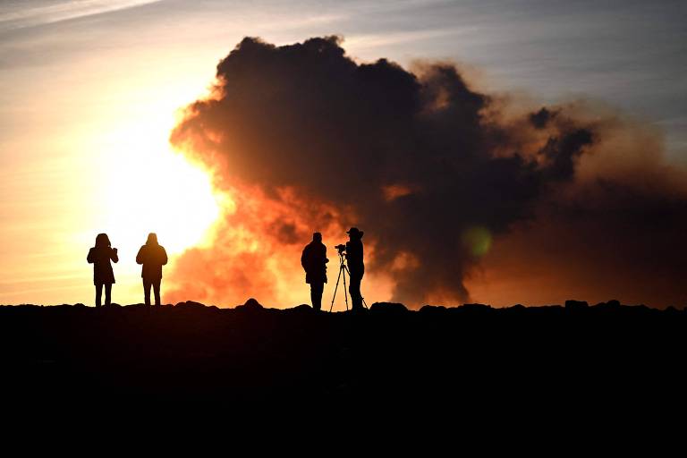 Pessoas assistem a erupção de vulcão perto da cidade de Grindavik, na Islândia