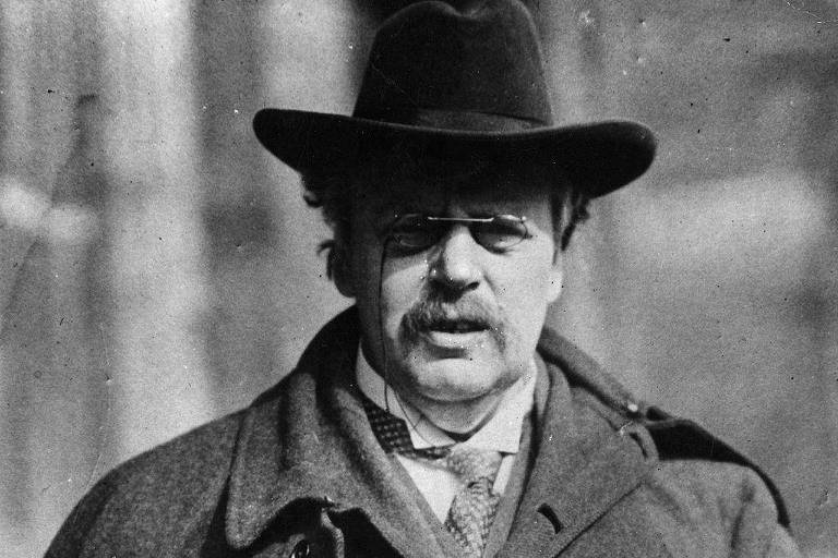 Chesterton com seu traje habitual de chapéu de abas largas, capa e pincenê. Arte foi feita por Joseph Simpson