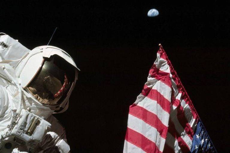 Pessoa com traje espacial perto de bandeira dos EUA