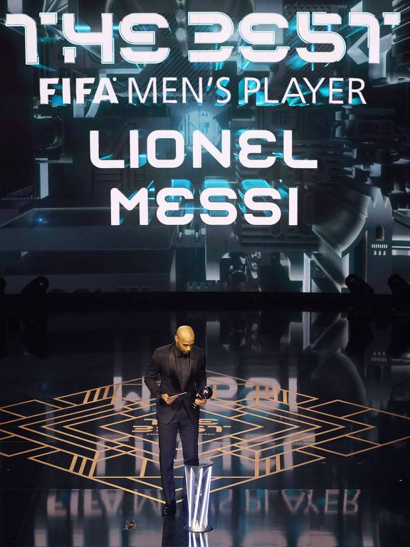 Constrangido, o francês Thierry Henry segura o prêmio The Best que deveria ser entregue ao argentino Lionel Messi, que não compareceu à festa da Fifa em Londres 
