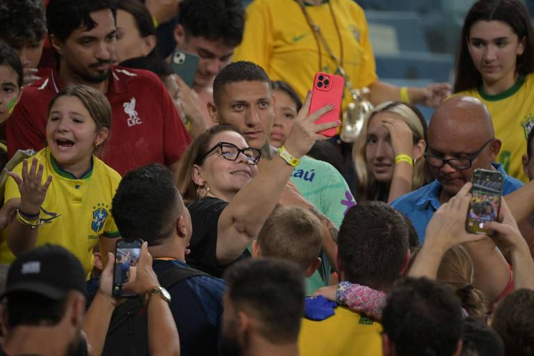 Richarlison, da seleção brasileira, tira selfie com torcedora no local destinado a fãs que puderam entrar na Arena Pantanal para ver treino da equipe