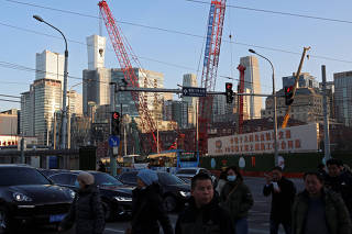 People cross an intersection near a construction site in Beijing