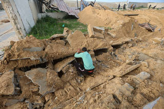 Palestinians check damaged graves at a cemetery following an Israeli raid, in Khan Younis