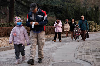 Elderly people walk with children at a park in Beijing