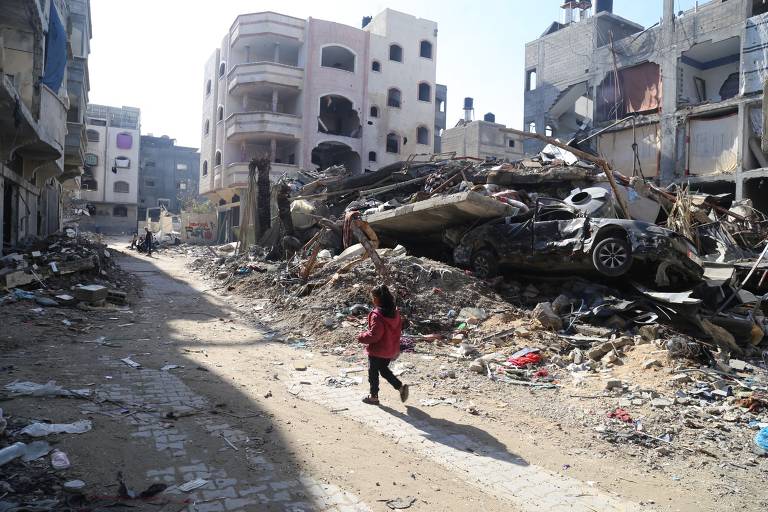 Palestina caminha em meio a prédios destruídos no campo de refugiados de Jabalia, no norte da Faixa de Gaza