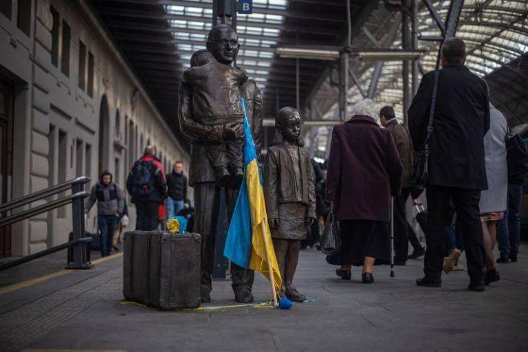Bandeira da Ucrânia encostada em estátua de um homem em plataforma ferroviária 