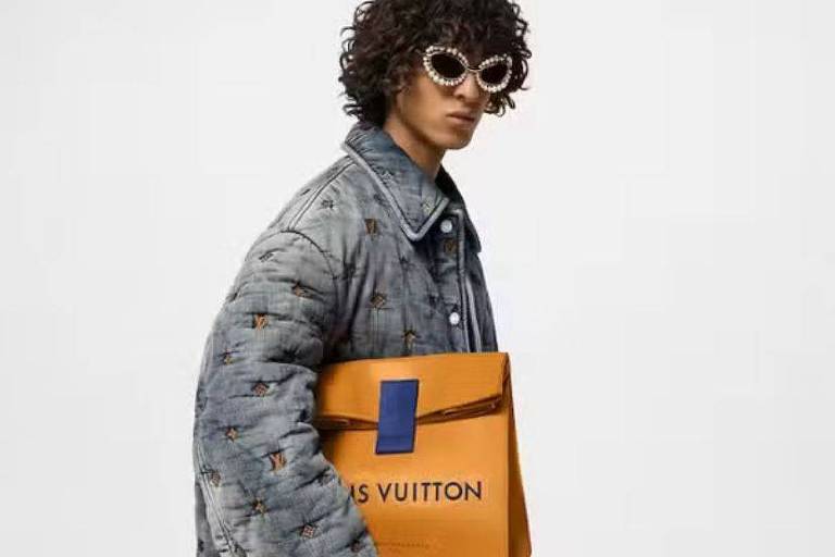 Homem segura uma bolsa amarela que se assemelha a um saco de pão e onde se lê "Louis Vuitton"