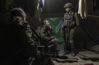 Capt. Amit Busi, right, of the Israeli Defense Forces, who commands a mixed-gender unit, talks to soldiers at an improvised military outpost on the front line in the northern Gaza Strip,  Dec. 25, 2023. (Avishag Shaar-Yashuv/The New York Times)