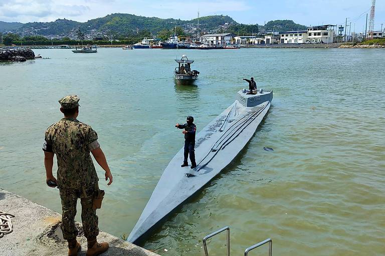 Um militar equatoriano está em um porto, de frente para outro, que está na superfície de um submarino que carregava drogas 