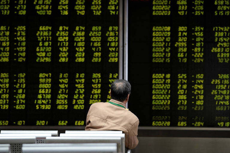 Investidor observa painel com cotações das ações na Bolsa de Pequim