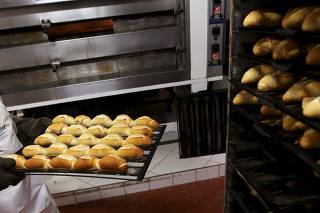 Employee carries a tray of baked bread at Nova Susi bakery in Sao Paulo, Brazil