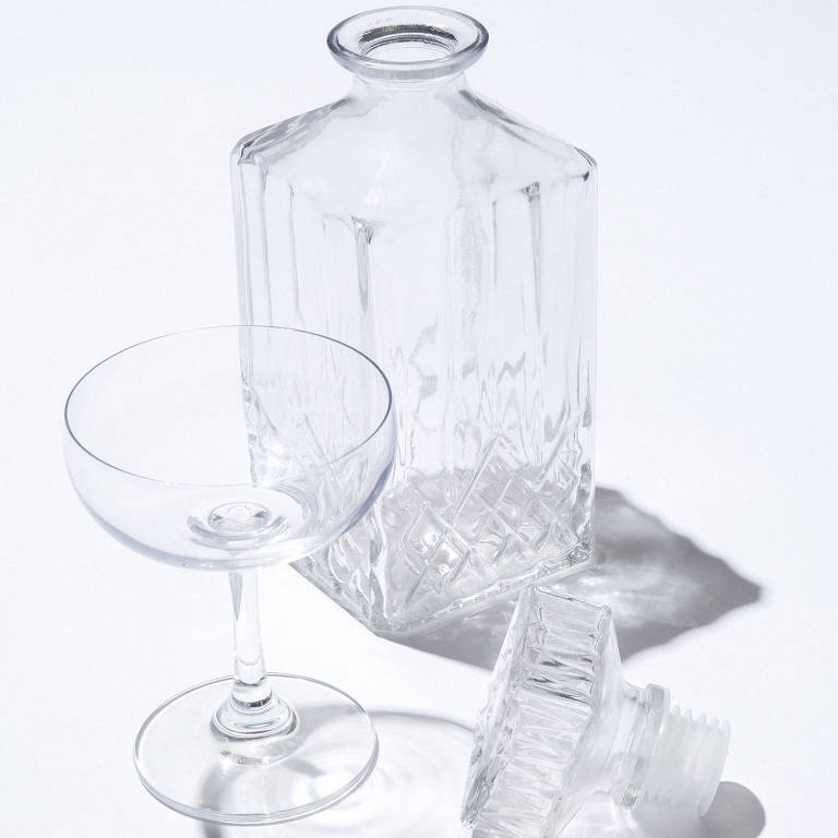 Fotografia de uma taça e uma garrafa, ambas transparentes e vazias