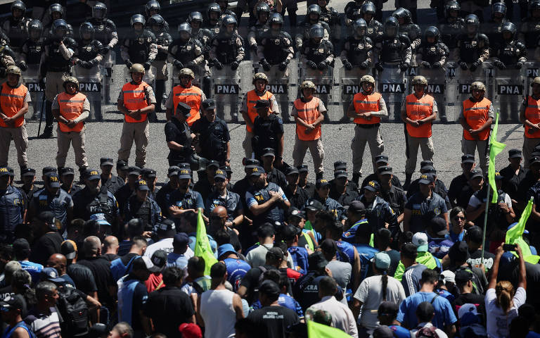 Membros da força policial marítima argentina em guarda diante de centenas de manifestantes perto da ponte Pueyrredón, em Buenos Aires, no dia de greve geral