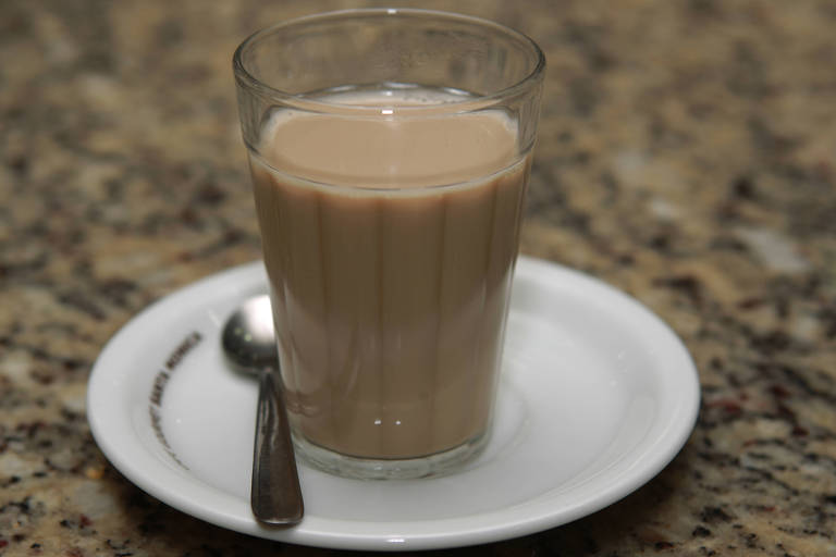 Café com leite em copo americano sobre um balcão de granito