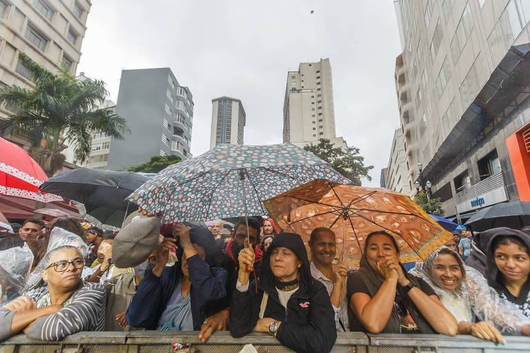 Moradores debaixo de chuva durante show do aniversário de São Paulo, no palco da avenida São João, no centro da cidade