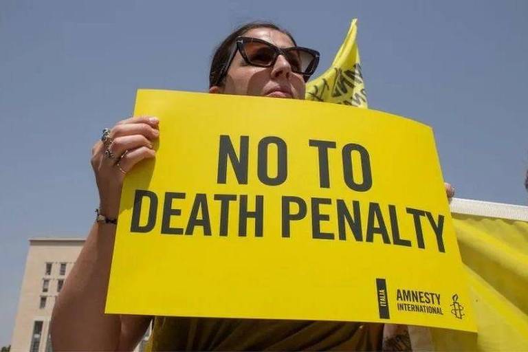 Mulher segura cartaz em inglês que pede fim das execuções