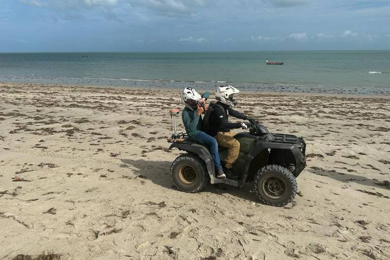 Imagem mostra duas pessoas em cima de um buggy em uma praia no Ceará