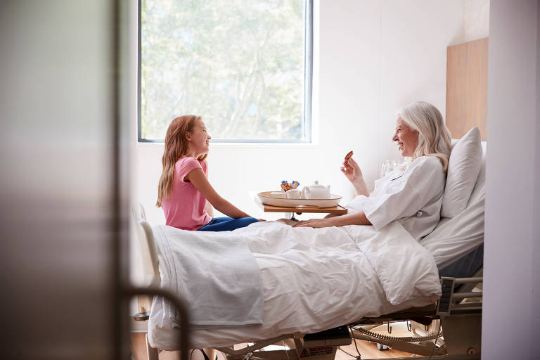 Neta visitando avó na cama de hospital para tomar chá da tarde