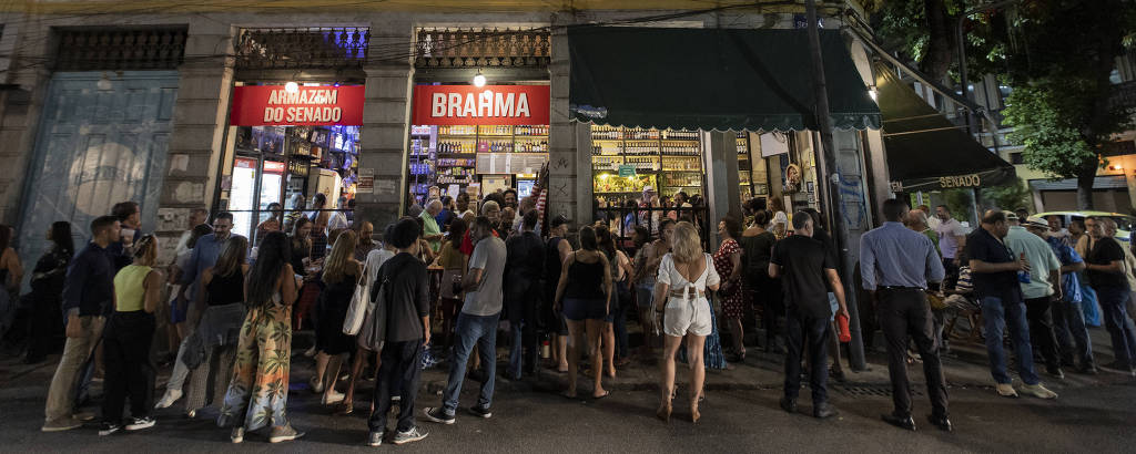 foto noturna com pessoas de pé em frente a bar em casarão no Rio