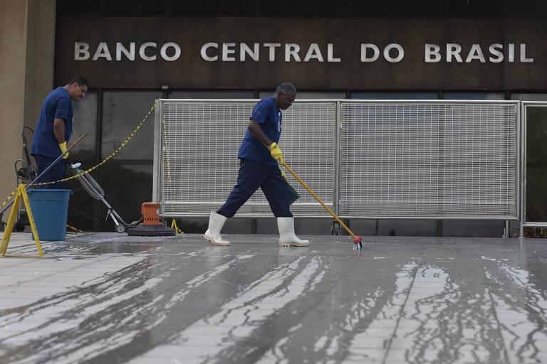 Trabalhadores limpam a fachada da sede do Banco Central em Brasília