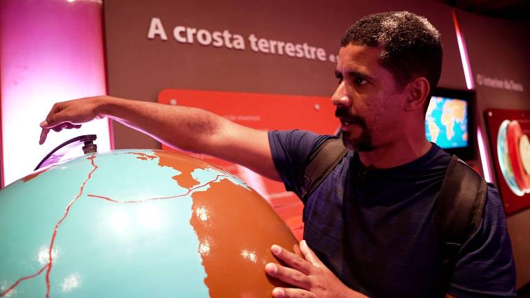 Leandro diante de um globo terrestre em exposição sobre o Universo, no Museu Catavento em São Paulo