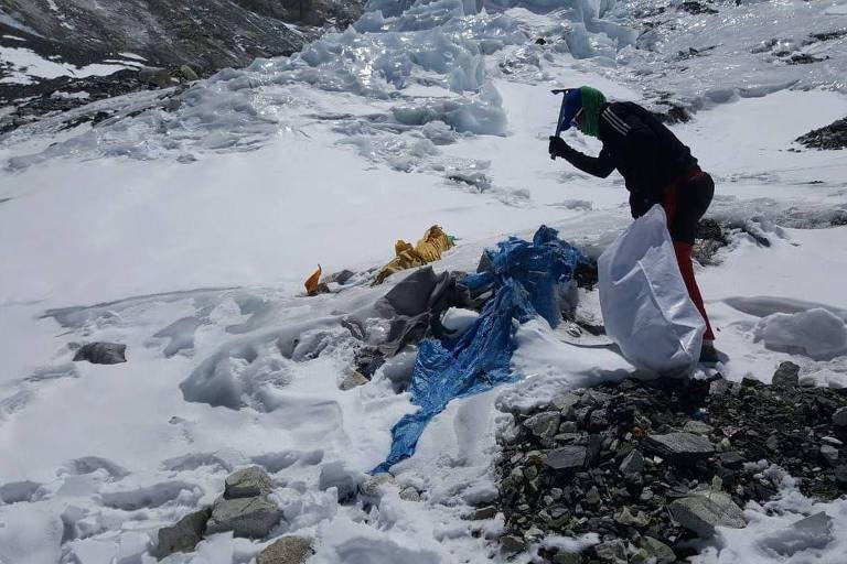 Uma pessoa junta sacos de lixo deixados em meio ao à neve e ao gelo no Monte Everest